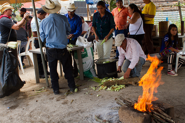 En el municipio de Casillas, en el departamento de Santa Rosa, en Guatemala, sus habitantes mantienen un bloqueo de la carretera que conduce a la mina de San Rafael Las Flores, para impedir el paso de suministros hacia el yacimiento. En la imagen, Rosa Dávila, en el centro, mientras pela mazorcas de maíz en el campamento improvisado de los activistas. Crédito: Edgardo Ayala/IPS